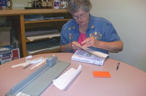 woman at table repairing a paperback book