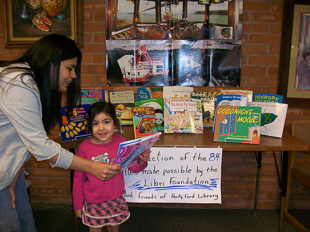 young girl and her mother looking at books arranged on a table