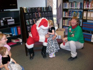 Santa Claus hugs child while parent and story teller laugh